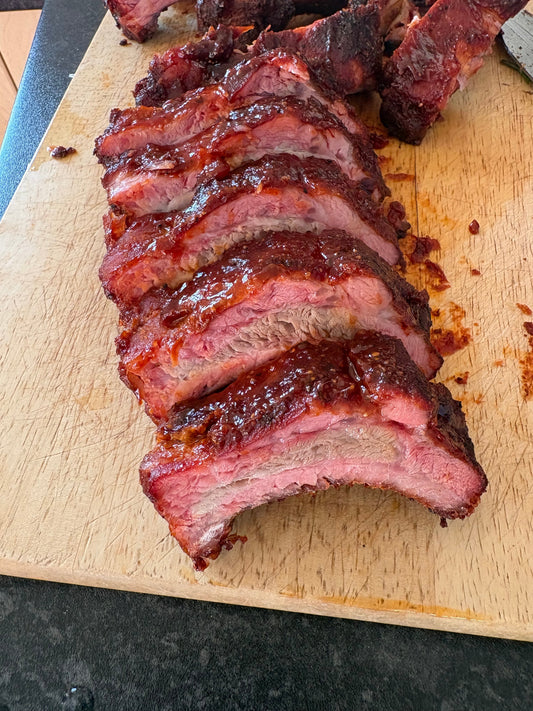 Sliced Sweet Piggy BBQ pork ribs on a wooden board