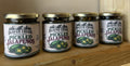 Four jars of Beaver Creek Pickled Jalapeños lined up on a wooden shelf